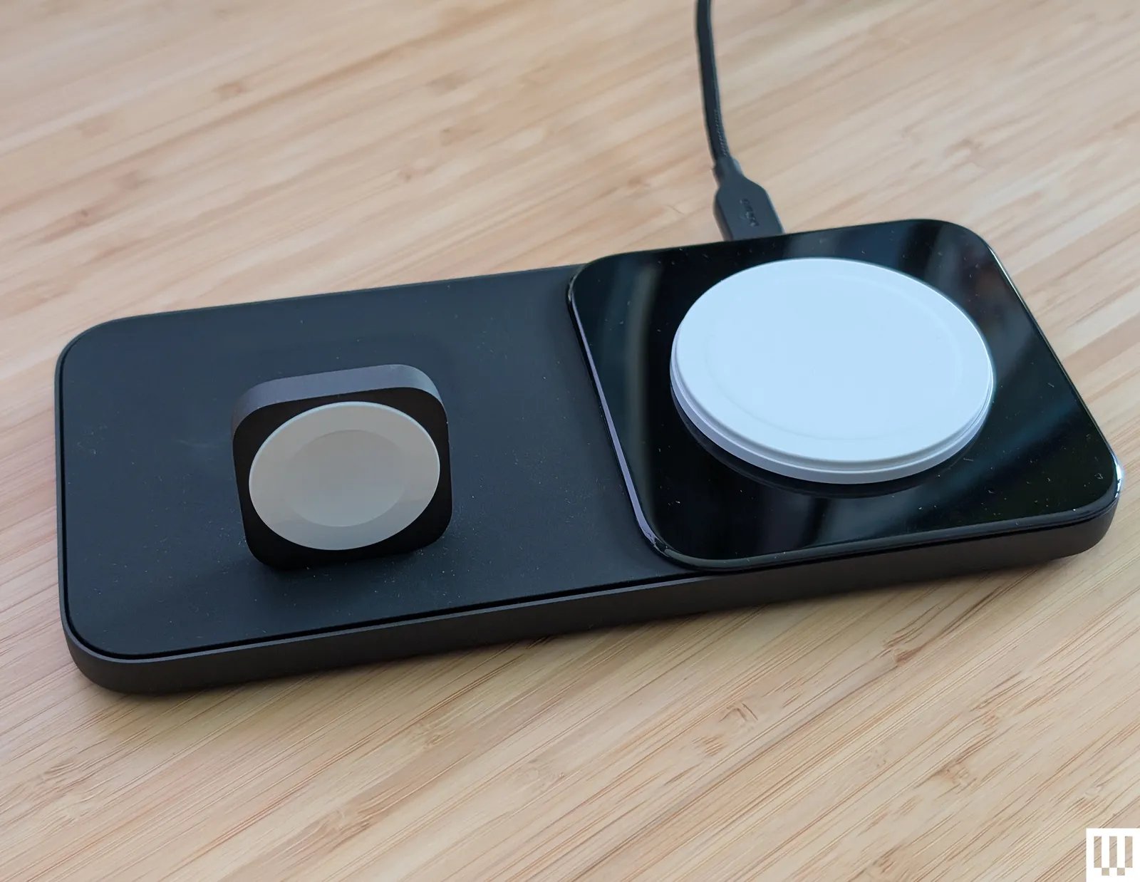 Nomad Base One Max a flat black panel with and upright square to wrap a watch around and a flat disc to place a mobile...